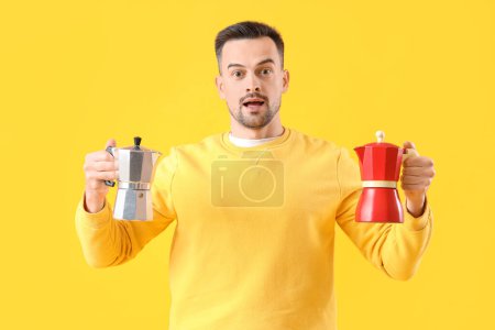 Handsome man with geyser coffee makers on yellow background