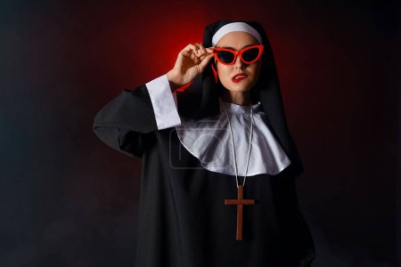 Freche Nonne mit Sonnenbrille auf dunklem Hintergrund