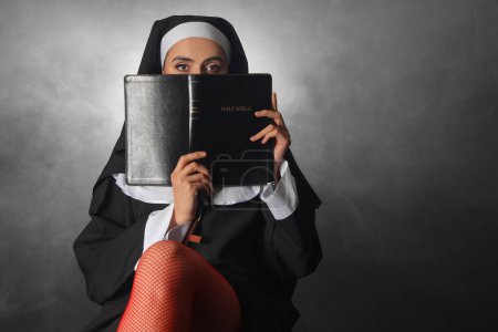 Freche Nonne mit Bibel und Rauch auf dunklem Hintergrund