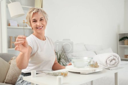 Photo for Mature woman preparing steam inhalation with herbs in bedroom - Royalty Free Image
