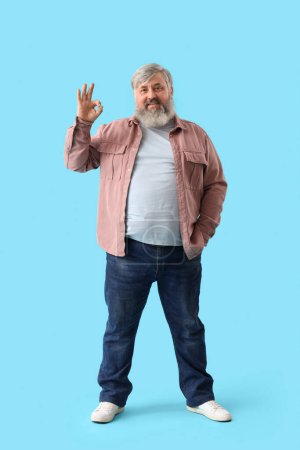 Photo for Mature bearded man showing OK on blue background - Royalty Free Image
