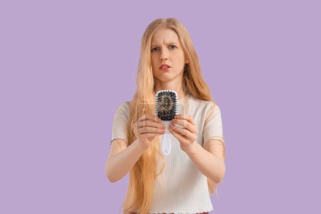 Téléchargez les photos : Jeune femme avec problème de perte de cheveux et brosse sur fond lilas - en image libre de droit