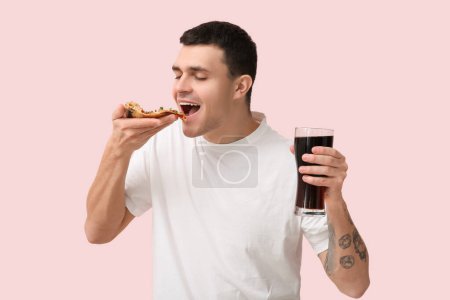 Photo for Young man holding piece of tasty pizza and glass of cola on pink background - Royalty Free Image