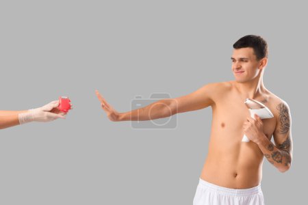 Photo for Young man rejecting epilator and choosing photoepilator instead on grey background - Royalty Free Image