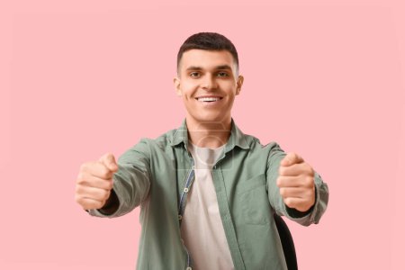 Junger Mann mit imaginärem Lenkrad auf rosa Hintergrund