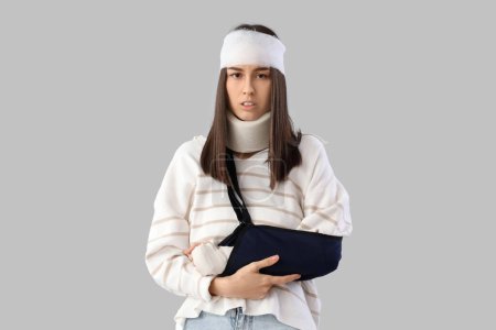 Téléchargez les photos : Jeune femme blessée après un accident avec un bras cassé sur fond clair - en image libre de droit