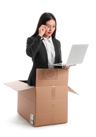 Foto de Divertida mujer de negocios asiática con portátil sentado en caja de cartón sobre fondo blanco - Imagen libre de derechos