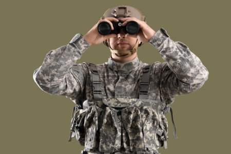 Male soldier in uniform looking through binoculars on green background