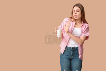 Téléchargez les photos : Jeune femme allergique à la peau et verre de lait sur fond brun - en image libre de droit