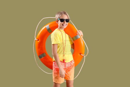 Photo for Happy little boy lifeguard in sunglasses with ring buoy on green background - Royalty Free Image