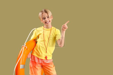 Photo for Happy little boy lifeguard with ring buoy pointing at something on green background - Royalty Free Image