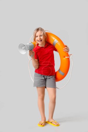 Photo for Happy little girl lifeguard with ring buoy and megaphone on grey background - Royalty Free Image
