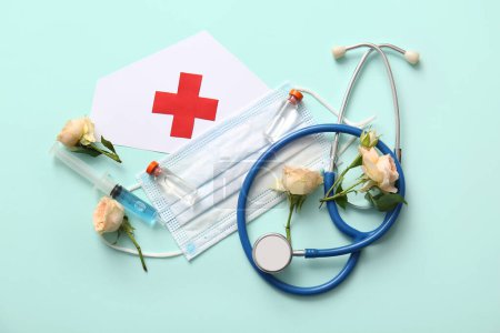 Photo for Paper medical hat with stethoscope, roses and ampules for International Nurses Day on turquoise background - Royalty Free Image