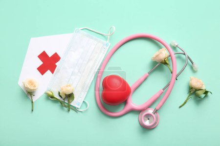 Stethoscope with roses, paper medical hat and mask for International Nurses Day on turquoise background