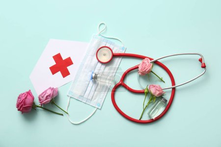 Stethoscope with roses, ampules and paper medical hat for International Nurses Day on turquoise background