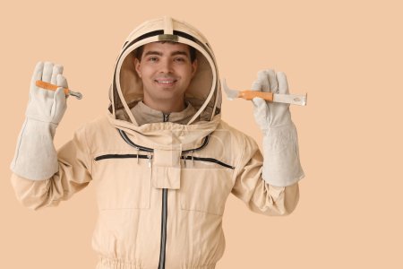 Male beekeeper with supplies on beige background