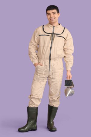 Male beekeeper with smoker on lilac background