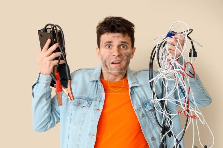 Electrocuted young man with burnt face and wires on beige background