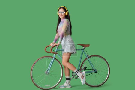 Téléchargez les photos : Belle jeune femme asiatique en casque avec vélo sur fond vert - en image libre de droit