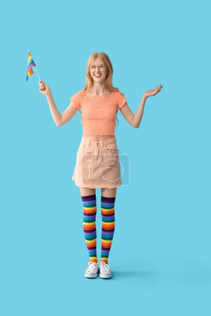 Hermosa joven feliz mujer en medias de arco iris con bandera LGBT sobre fondo azul