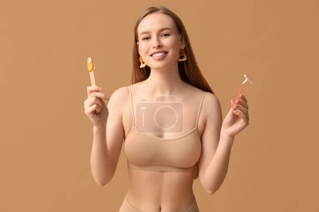 Photo for Beautiful young happy woman holding razor and spatula with sugaring paste on beige background - Royalty Free Image