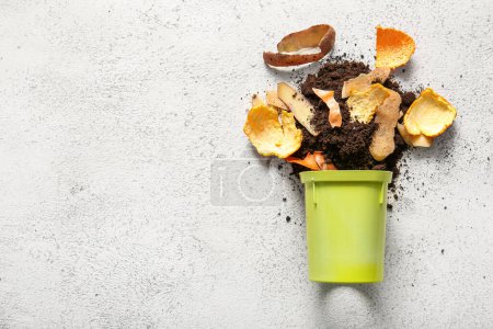 Bin with organic waste and soil on white grunge background. Compost recycling concept