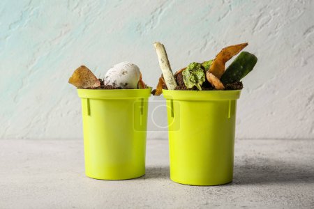 Buckets with organic waste and soil on white grunge table. Compost recycling concept