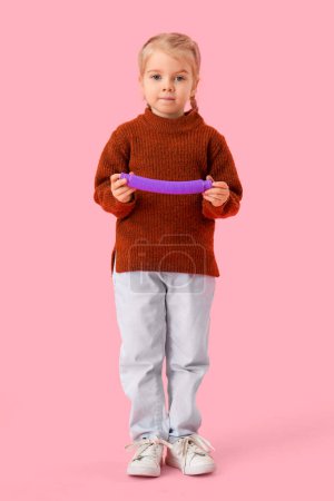 Little girl with autistic disorder and Pop Tube on pink background