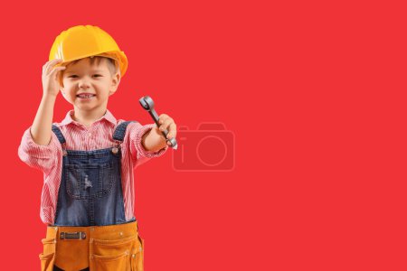 Téléchargez les photos : Mignon petit constructeur avec clé à jouet sur fond rouge - en image libre de droit
