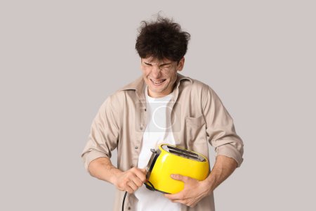 Electrocuted young man with burnt face and toaster on light background