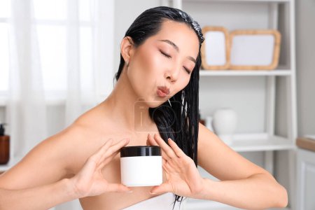 Téléchargez les photos : Jeune femme asiatique avec pot de masque de cheveux soufflant baiser dans la salle de bain, gros plan - en image libre de droit