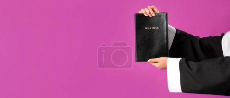 Foto de Manos de monja joven sosteniendo la Biblia sobre fondo púrpura con espacio para el texto - Imagen libre de derechos