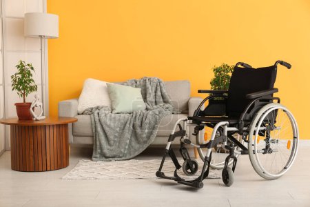 Foto de Moderna silla de ruedas vacía en sala de estar cerca de la pared amarilla - Imagen libre de derechos
