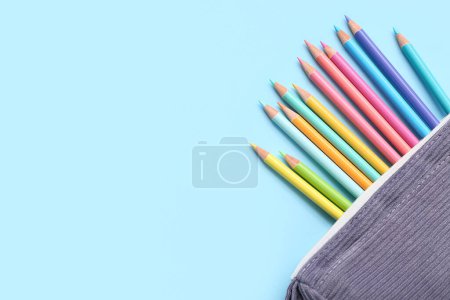 Foto de Estuche con muchos lápices de colores sobre fondo azul - Imagen libre de derechos