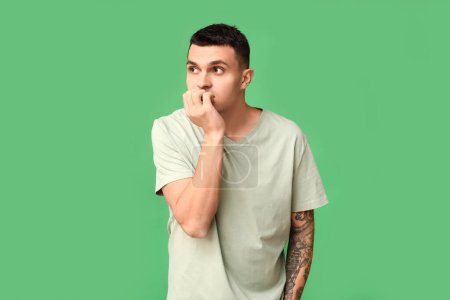 Photo for Handsome ashamed young man on green background - Royalty Free Image