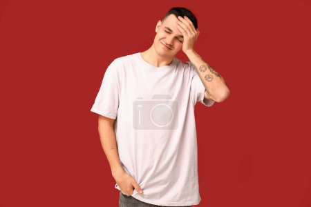 Photo for Handsome ashamed young man covering face with hand on red background - Royalty Free Image