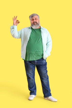 Photo for Mature bearded man showing OK on yellow background - Royalty Free Image
