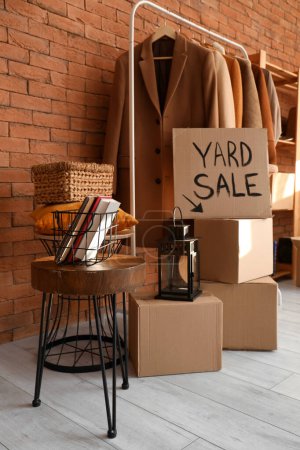 Photo for Cardboard with text YARD SALE and various unwanted things near brick wall in room - Royalty Free Image