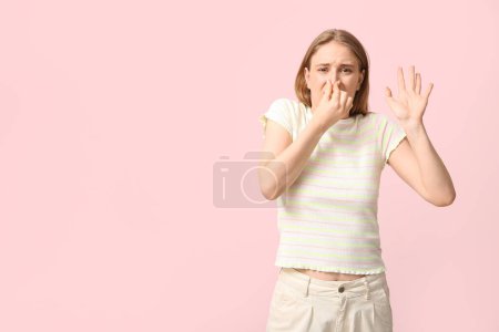 Photo for Young woman feeling disgusting smell on pink background - Royalty Free Image