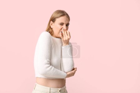 Photo for Young woman feeling disgusting smell on pink background - Royalty Free Image