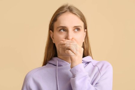 Photo for Young woman feeling disgusting smell on beige background - Royalty Free Image