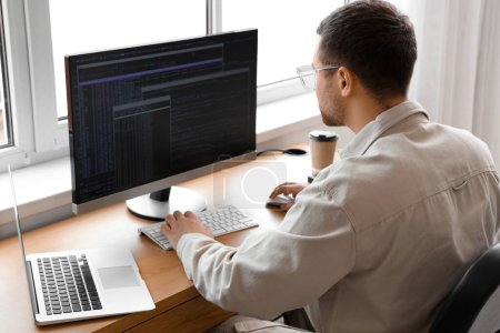 Téléchargez les photos : Programmeur masculin concentré travaillant dans le bureau - en image libre de droit