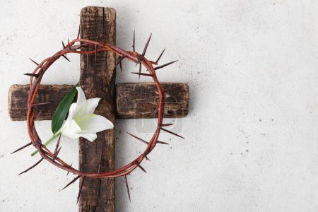 Wooden cross with crown of thorns and lily on grunge background