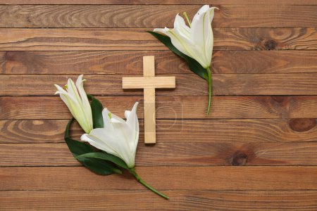 White lilies and cross on wooden background