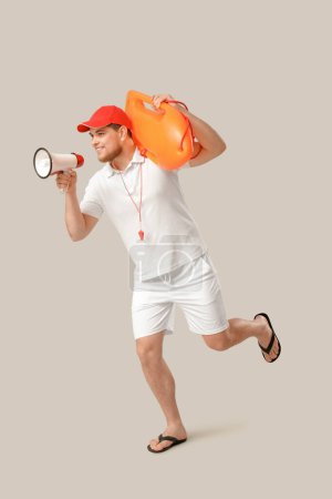 Photo for Young male lifeguard with rescue buoy and megaphone running on grey background - Royalty Free Image