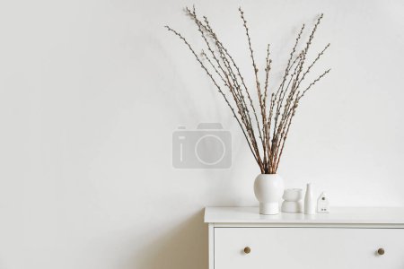 Foto de Jarrón con ramas de sauce en la cómoda en la sala de estar de luz - Imagen libre de derechos