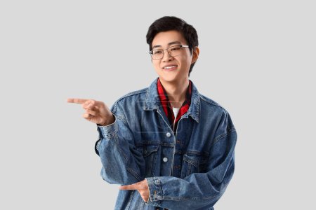 Photo for Young Asian man pointing at something on light background - Royalty Free Image