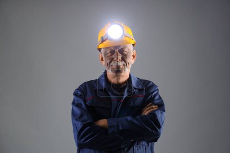 Mature miner man with headlamp on grey background