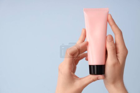 Mains féminines avec tube de crème naturelle sur fond de couleur, gros plan