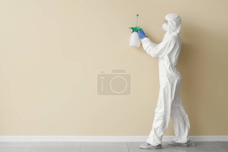 Trabajadora de servicio de limpieza quitando moho de la pared beige
